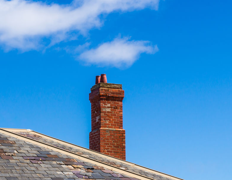 The old brick chimney on the roof in the countryside