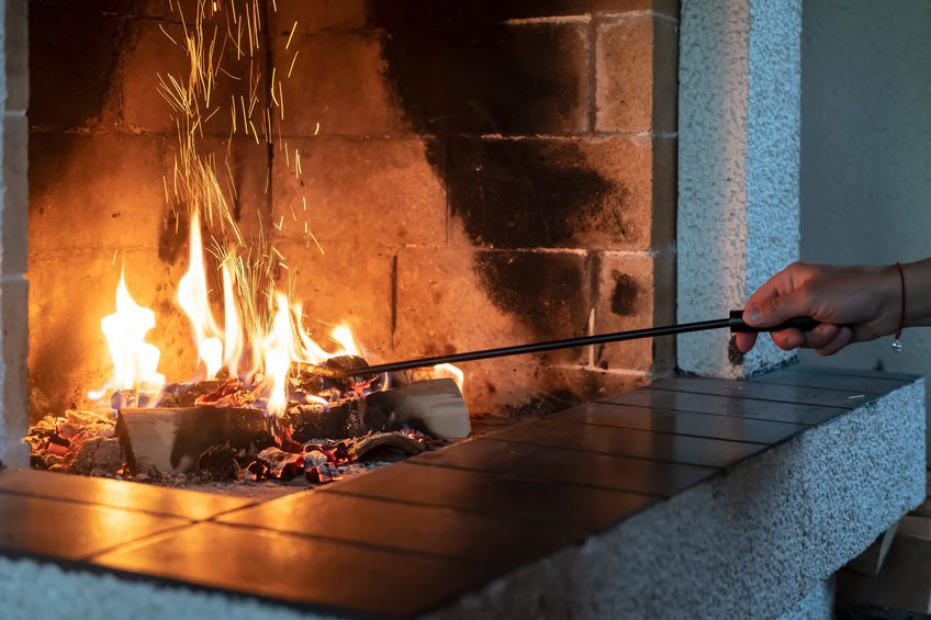 Fireplace with a female hand straightening logs